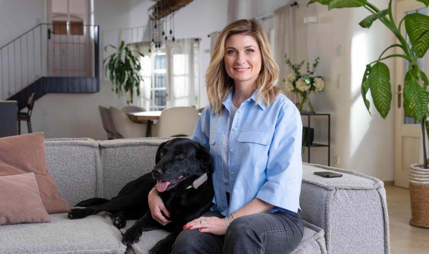 A woman sitting with a dog that's wearing a Tractive device