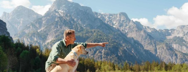 Ein Mann im Freien mit einem Hund, der einen Tractive GPS & Health Tracker trägt
