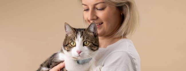 woman holding a cat wearing a tractive cat tracker and cat heart rate monitor