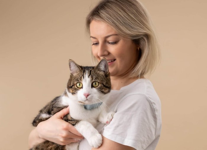woman holding a cat wearing a tractive cat tracker and cat heart rate monitor