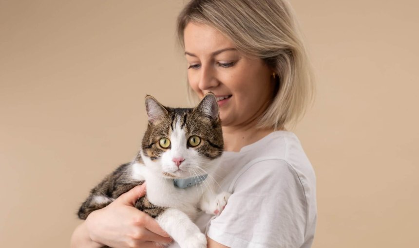 woman holding a cat wearing a tractive cat tracker and cat heart rate monitor