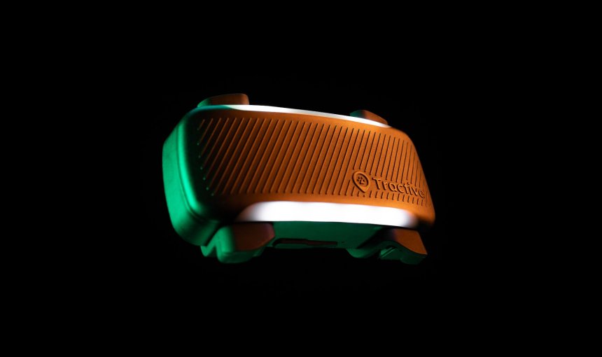 Primo piano del GPS Tractive con luce LED accesa su sfondo nero