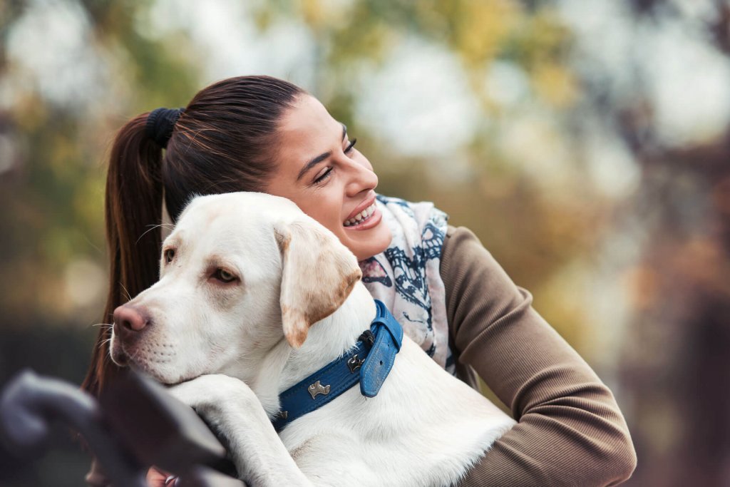 woman hugging white lab dog