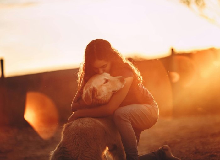 A woman hugging a dog outdoors