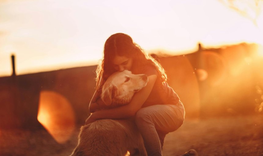 A woman hugging a dog outdoors