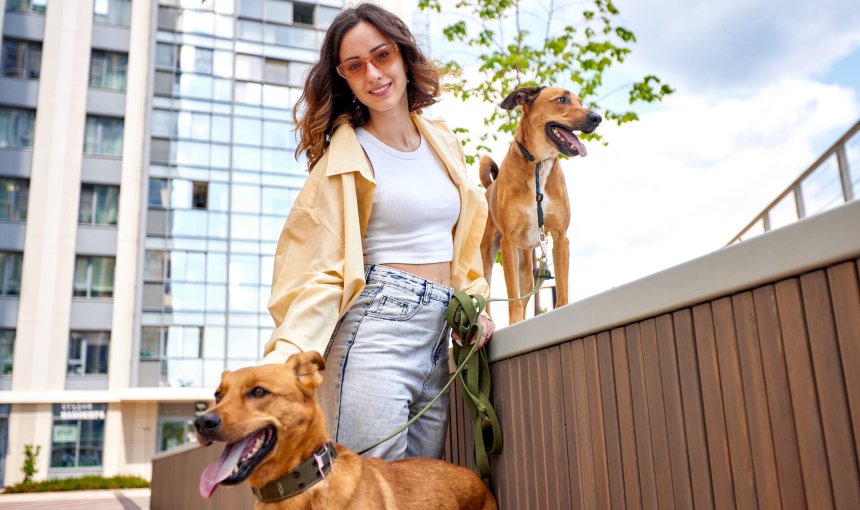 A young woman outside a city building with two dogs