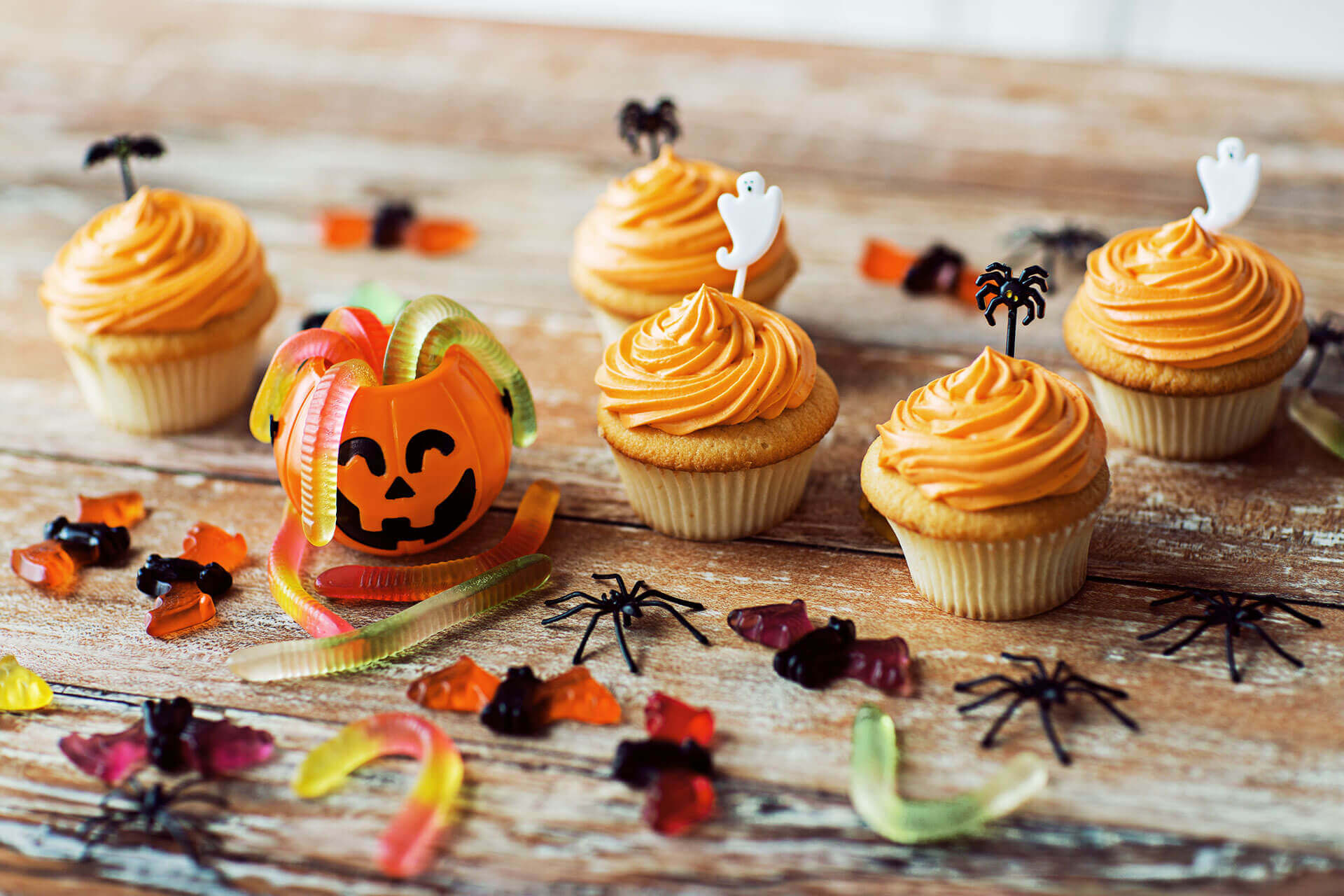 Halloween candy, cupcakes, and decorations on wooden table - halloween safety tips for dogs
