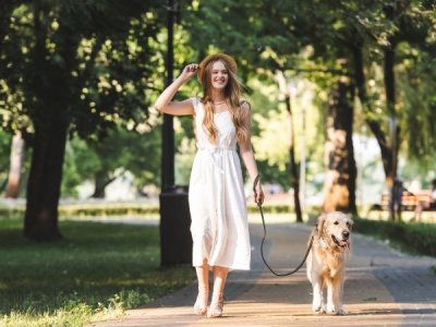 Frau in Sommerkleid beim Gassi gehen mit Hund