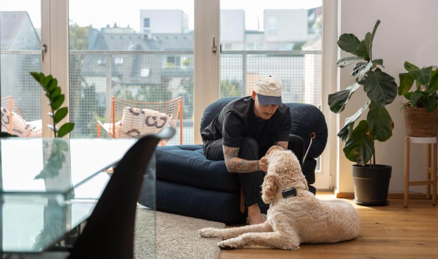 Mann streichelt Hund im Haus