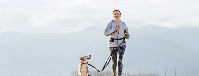 Joggerin läuft mit Hund an der Leine