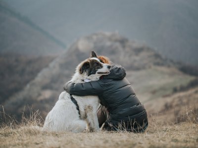 man and dog in embrace - white dog wearing Tractive GPS dog tracker