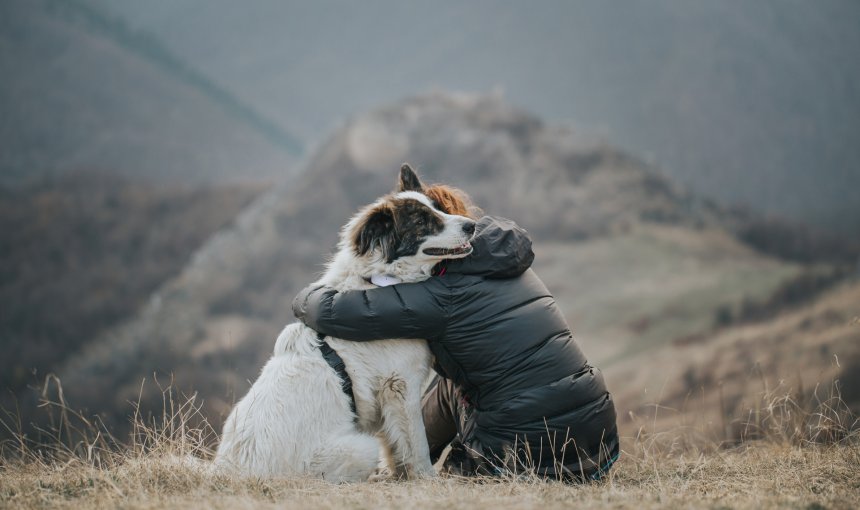 man and dog in embrace - white dog wearing Tractive GPS dog tracker