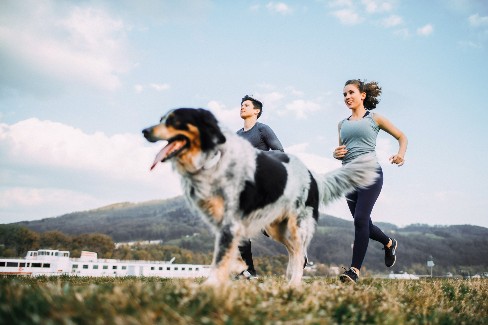 man and woman running with dog