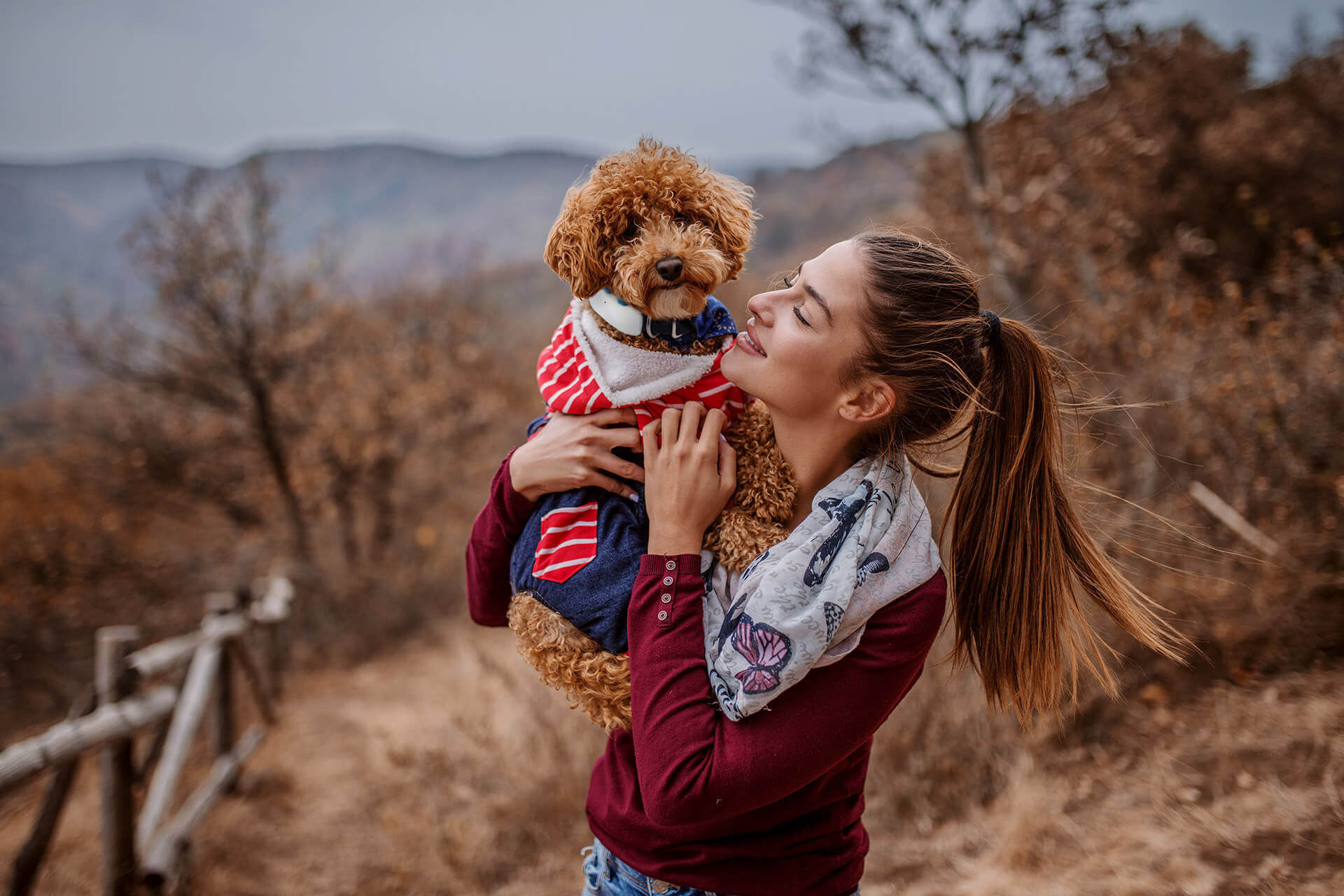 Femme tenant dans ses bras un chien avec un traceur GPS