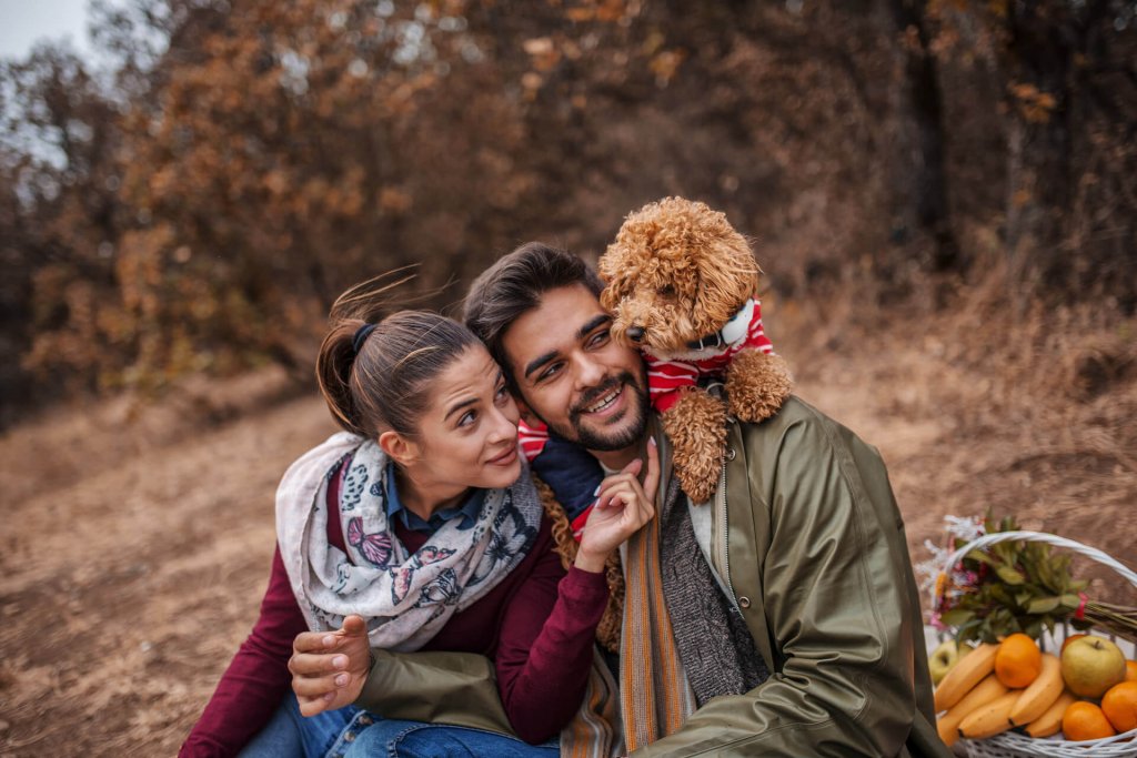 hombre, mujer y perro con localizador GPS posando al aire libre