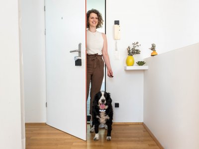 Frau mit Hund öffnet Tür mit Smart Lock