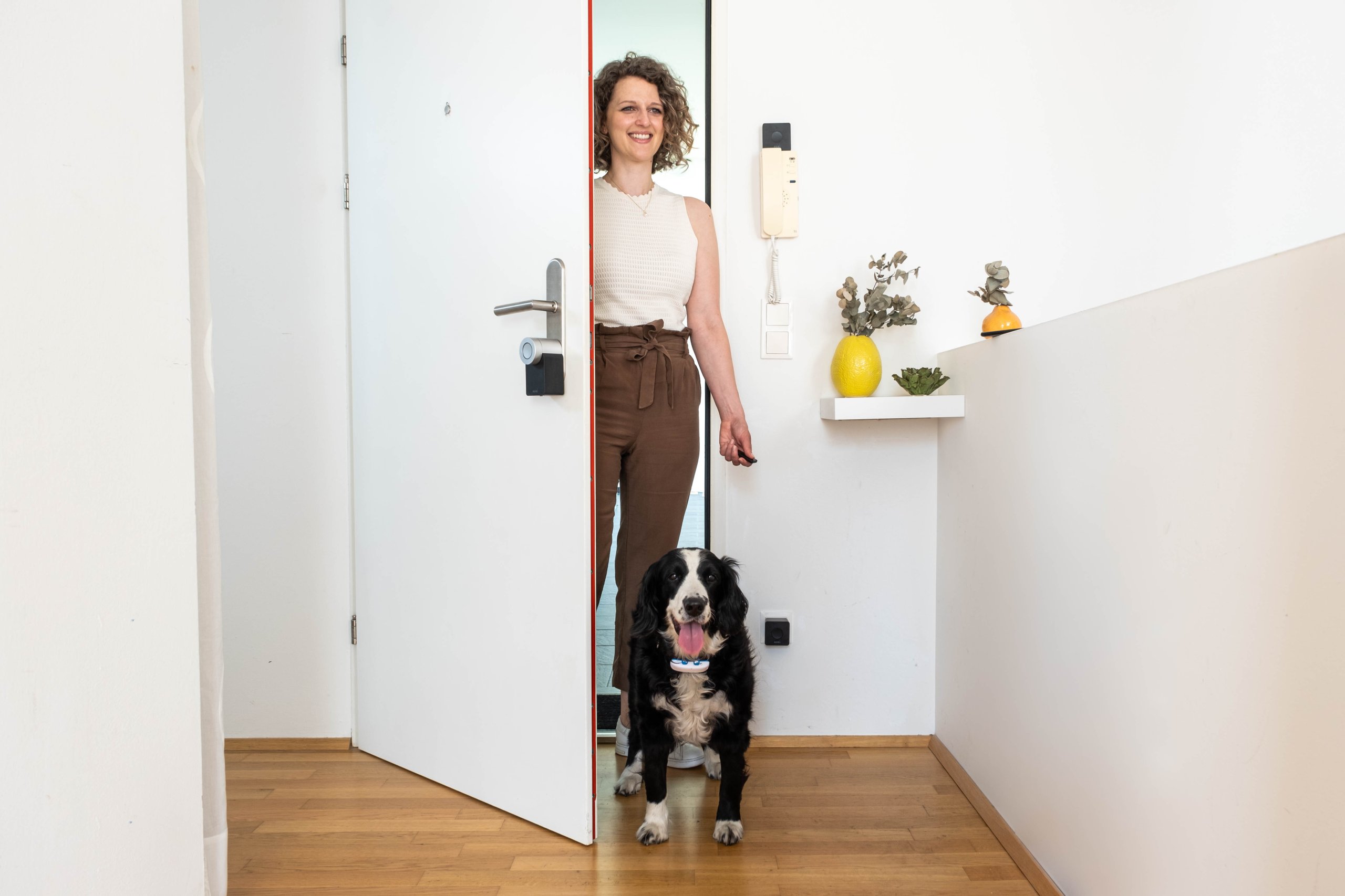 Frau mit Hund öffnet Tür mit Smart Lock