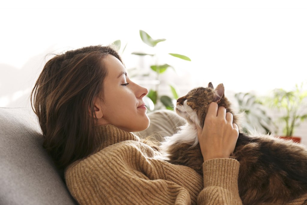 woman cuddling cat on couch