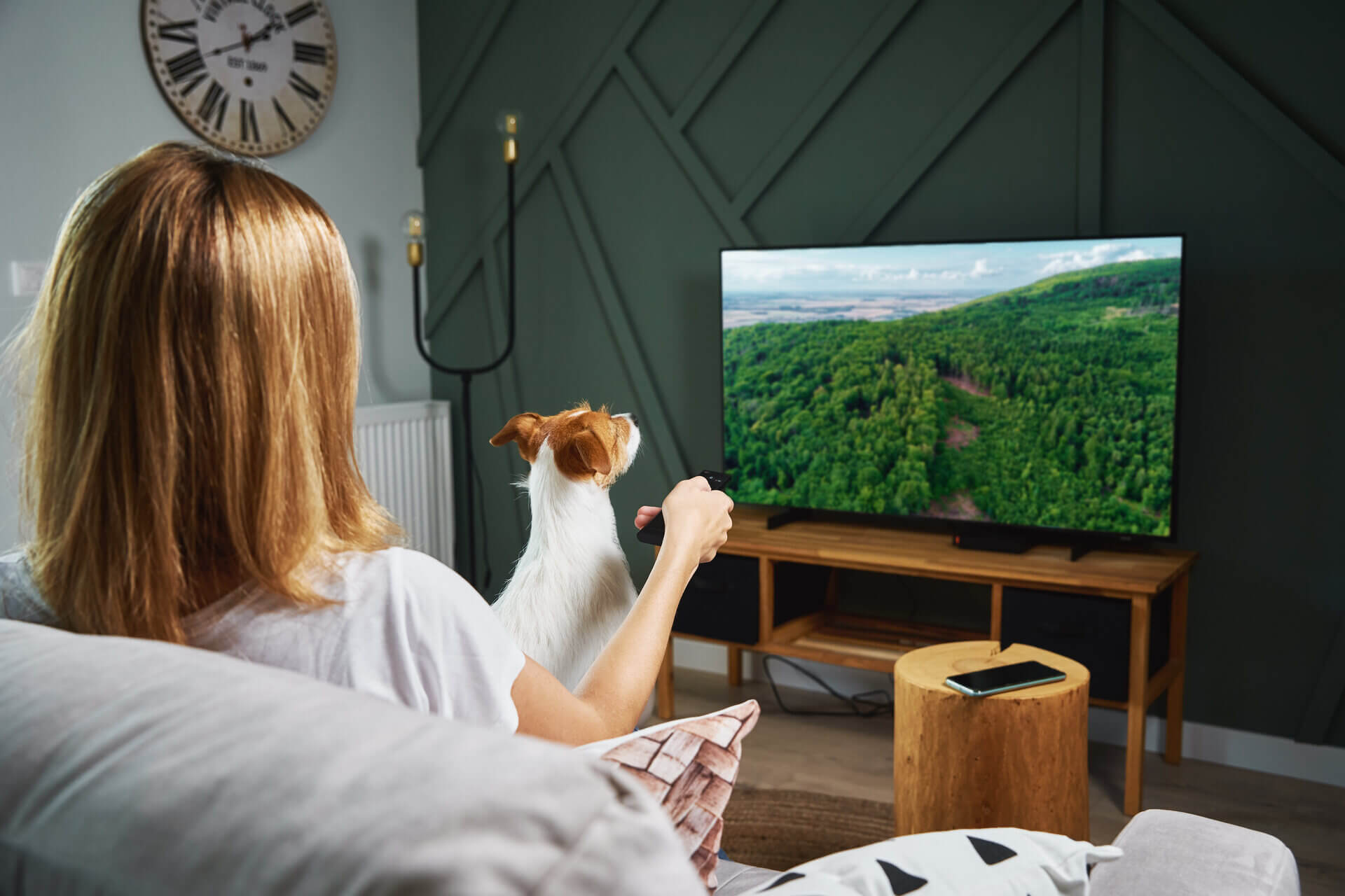 A woman watching TV with her dog