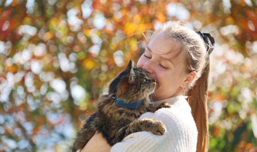 femme tenant un chat brun avec un collier GPS Tractive dans ses bras