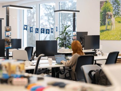 woman working at computer in office with a welcome banner in the background