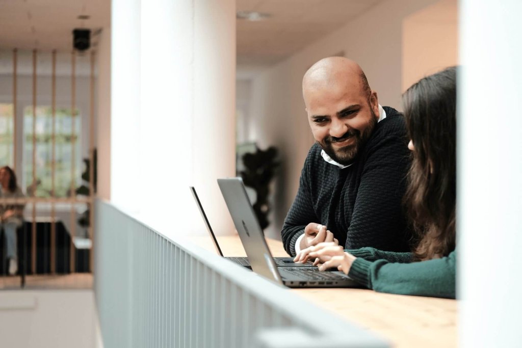 man and woman working at computers talking in an office