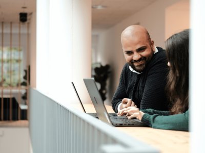 man and woman working at computers talking in an office