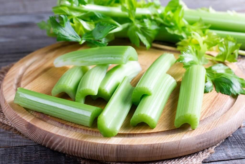 Trozos de apio en una tabla de cortar de madera