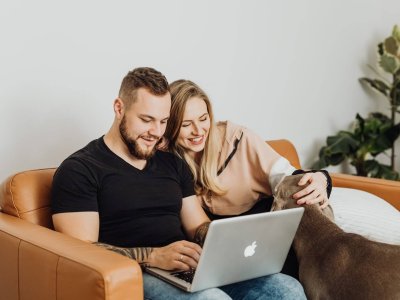 man and woman looking at a laptop with dog