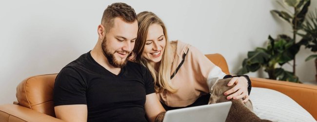 man and woman looking at a laptop with dog