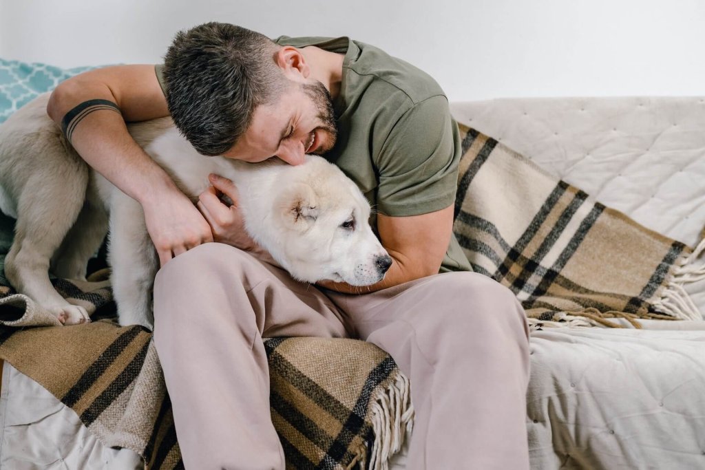 man hugging dog on a couch