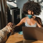 A woman drinking coffee next to her dog