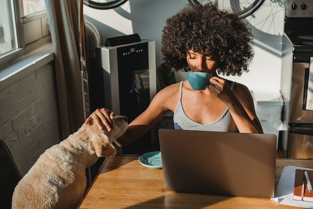 Een vrouw die koffie drinkt naast haar hond