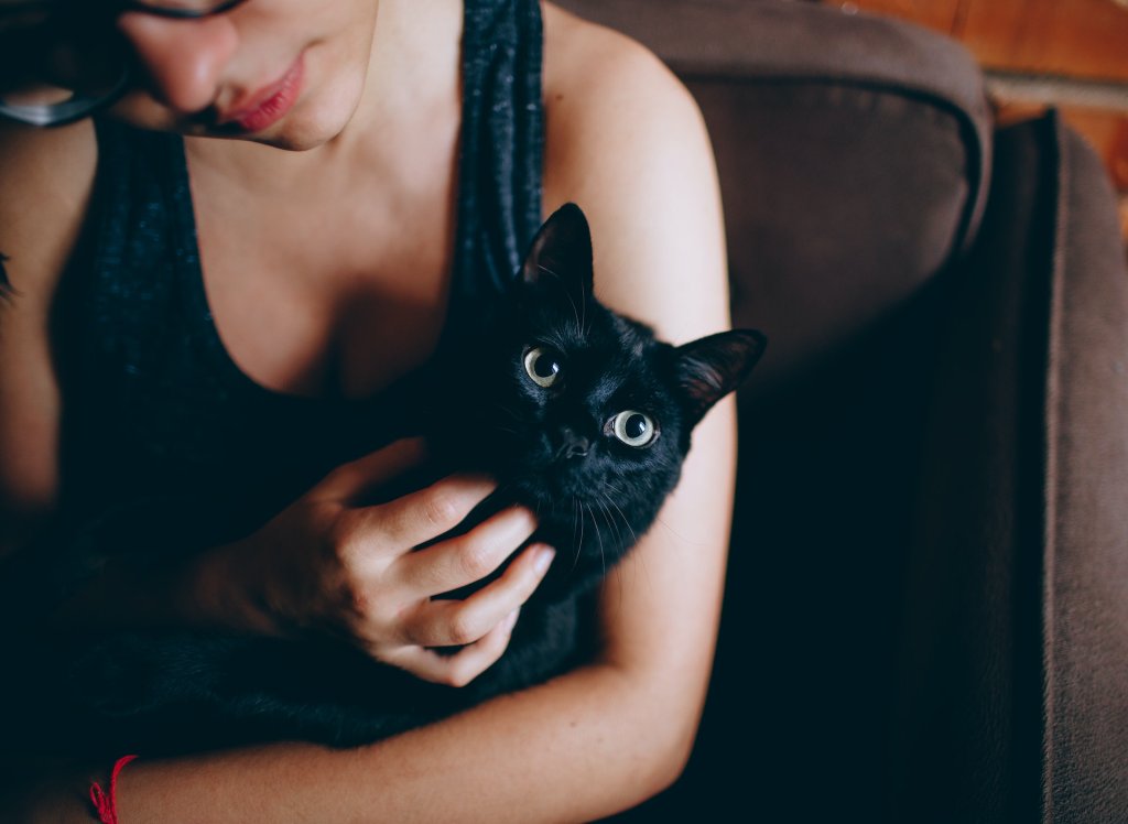 A woman hugging a black cat