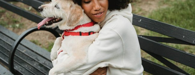 woman hugging dog on a bench outside