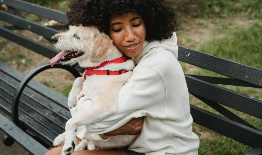 woman hugging dog on a bench outside