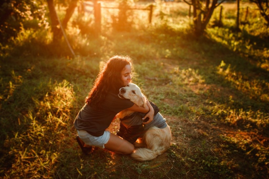 Frau umarmt Hund auf einer Wiese