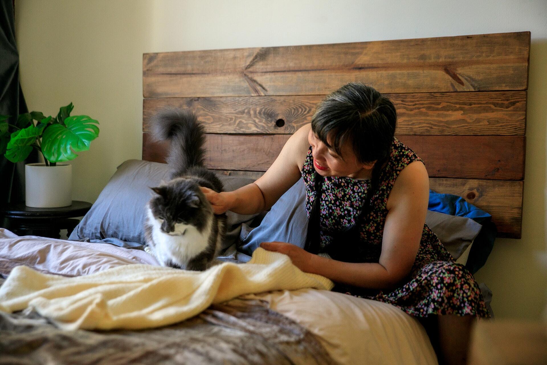 A woman stroking a cat in bed