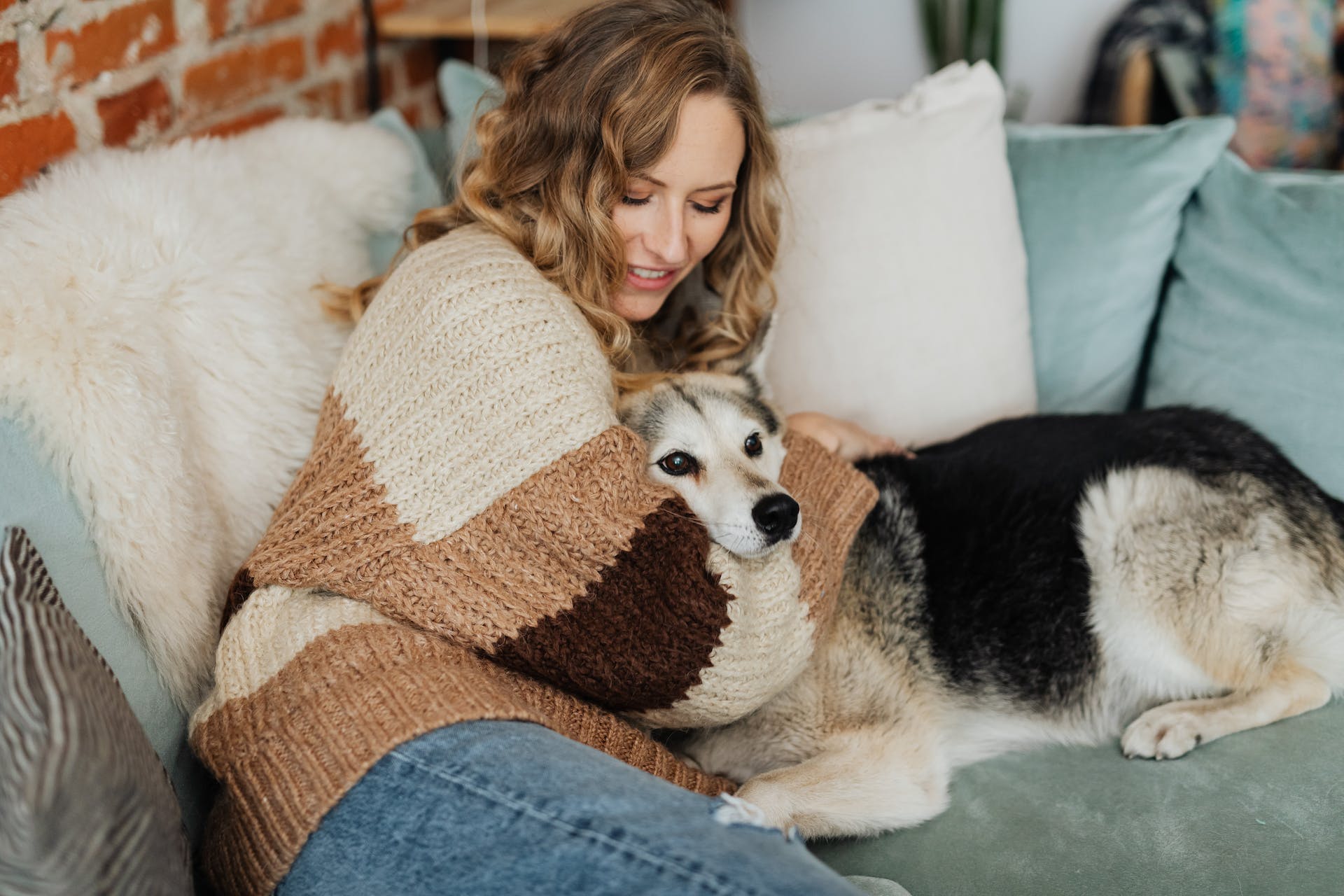 Kvinna som kramar hund på soffa