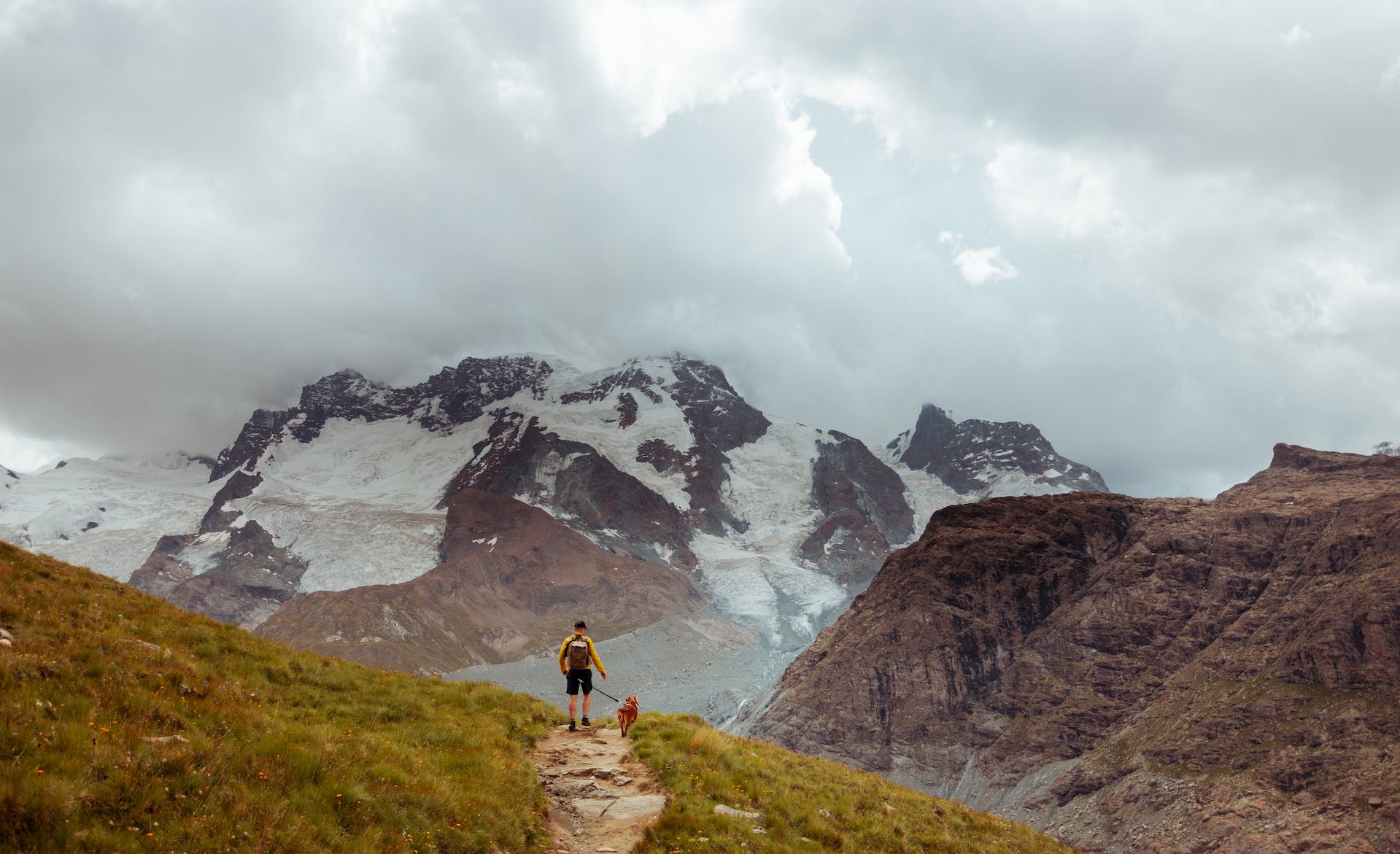 A man walking his dog on a leash in the mountains