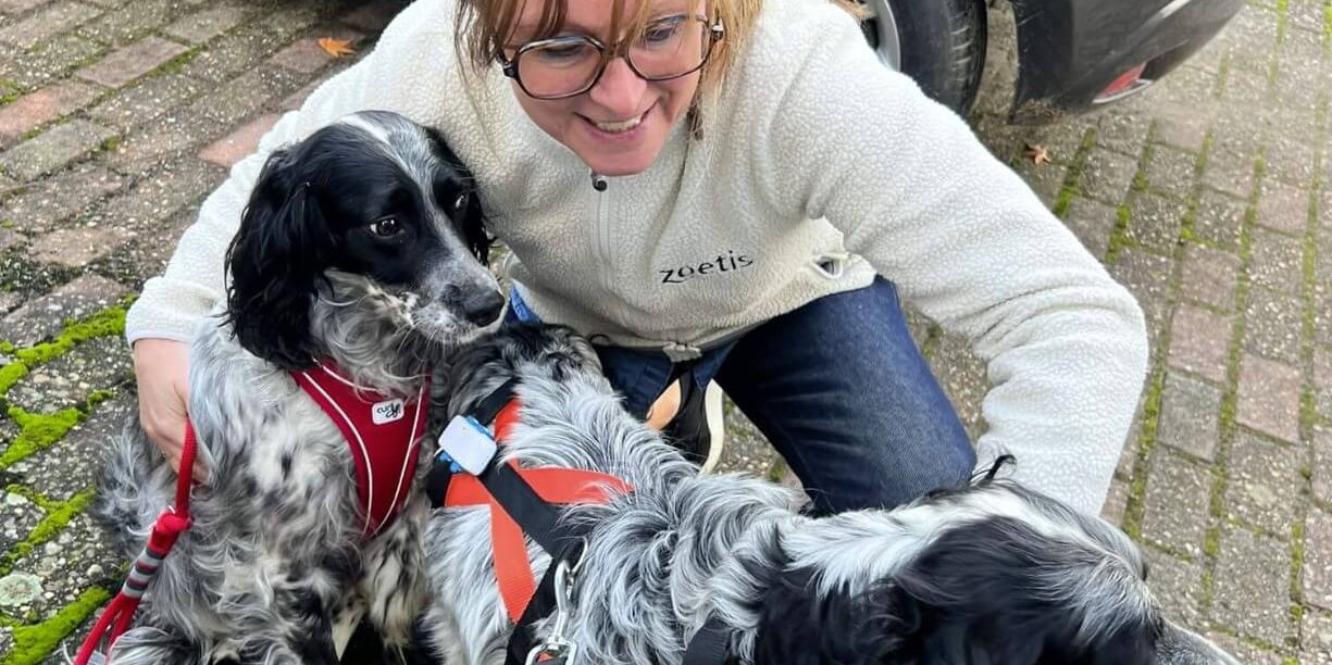 A woman hugging two rescued Setters that are wearing Tractive GPS trackers