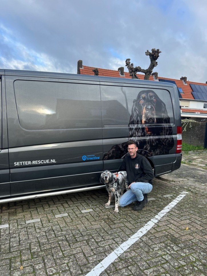 Alex Voenken sitting by a transport van with one of his rescue dogs