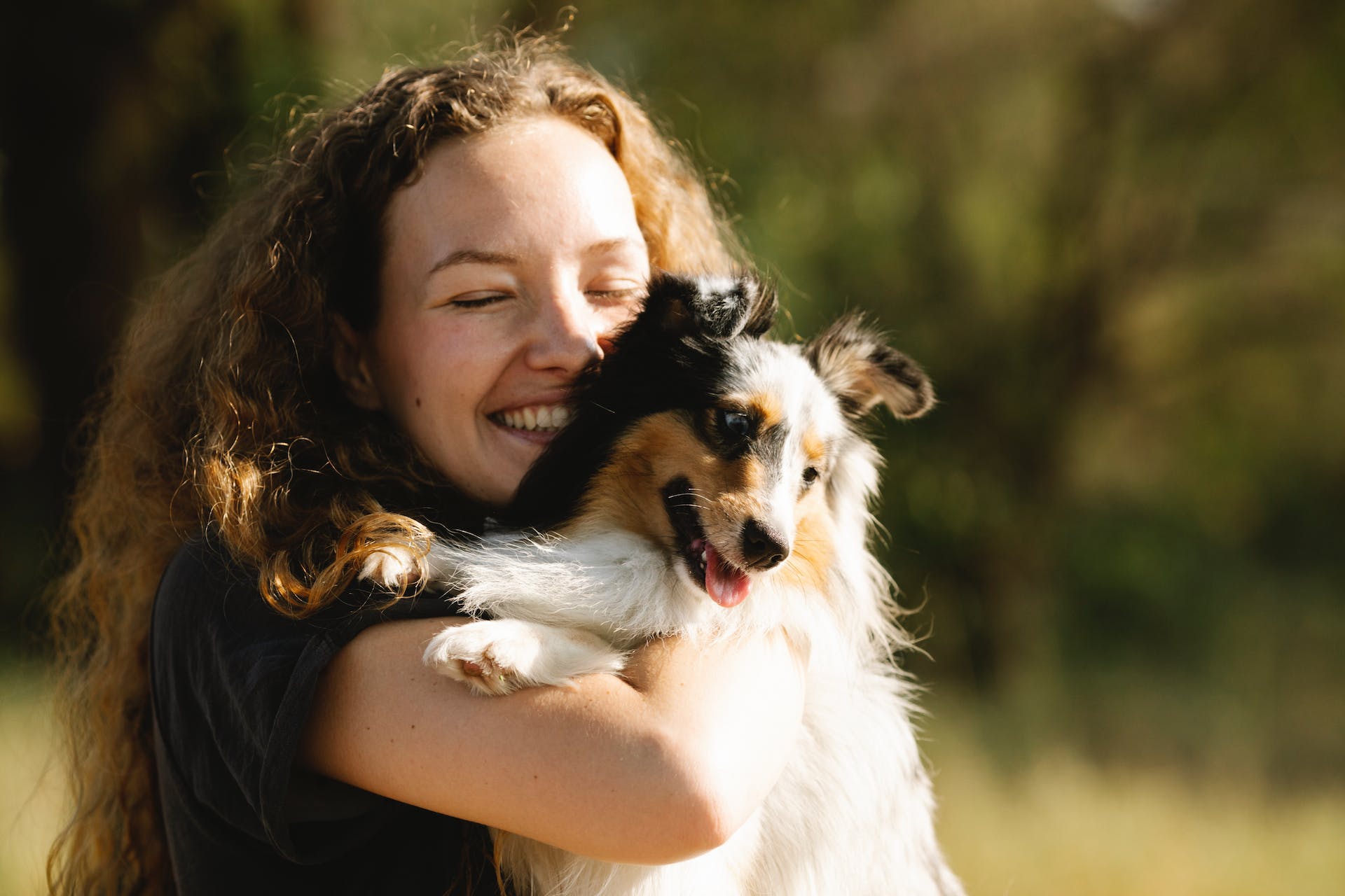 jeune femme souriante tenant un petit chien noir et blanc dans ses bras