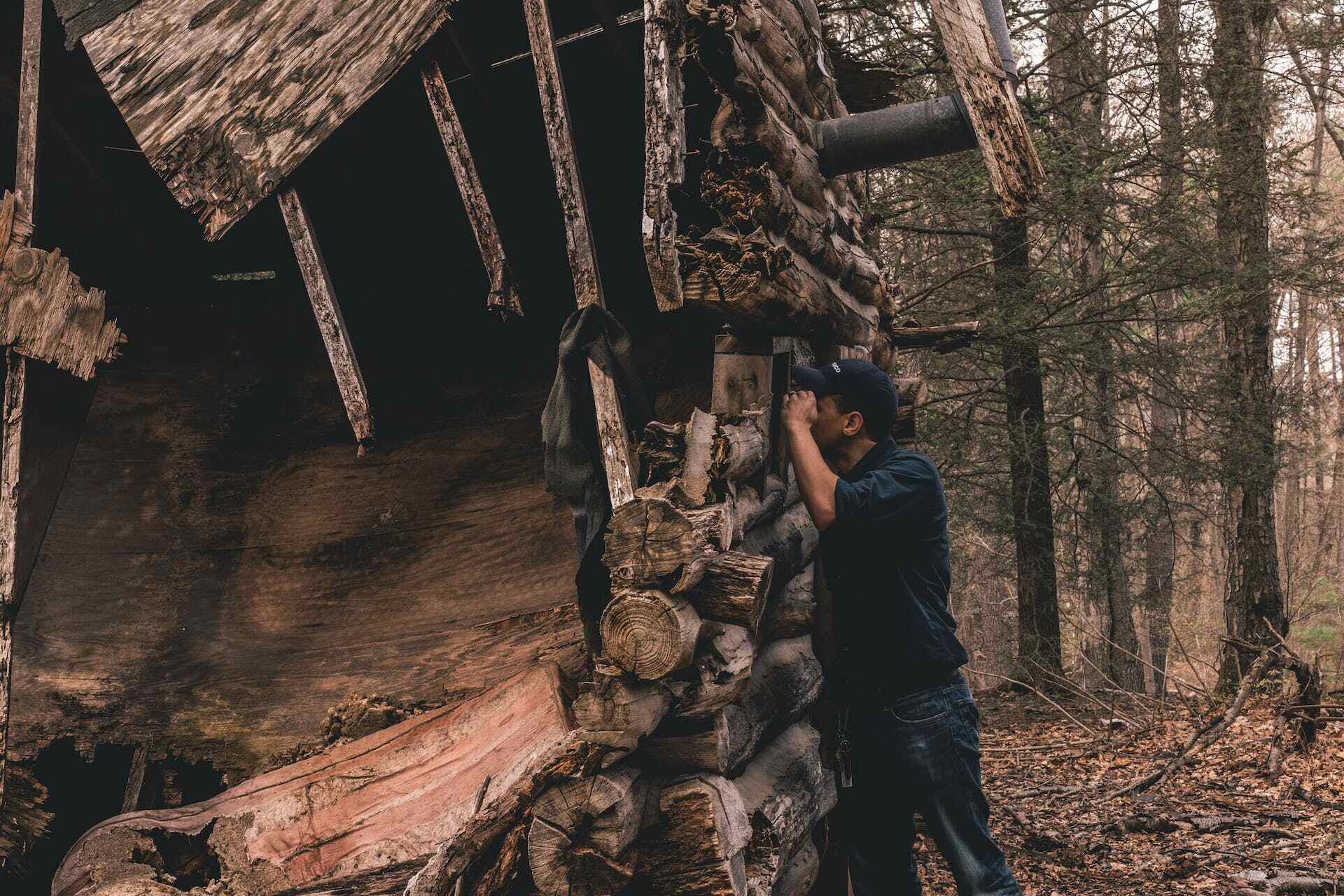 A man searching for a lost cat outdoors near a log cabin