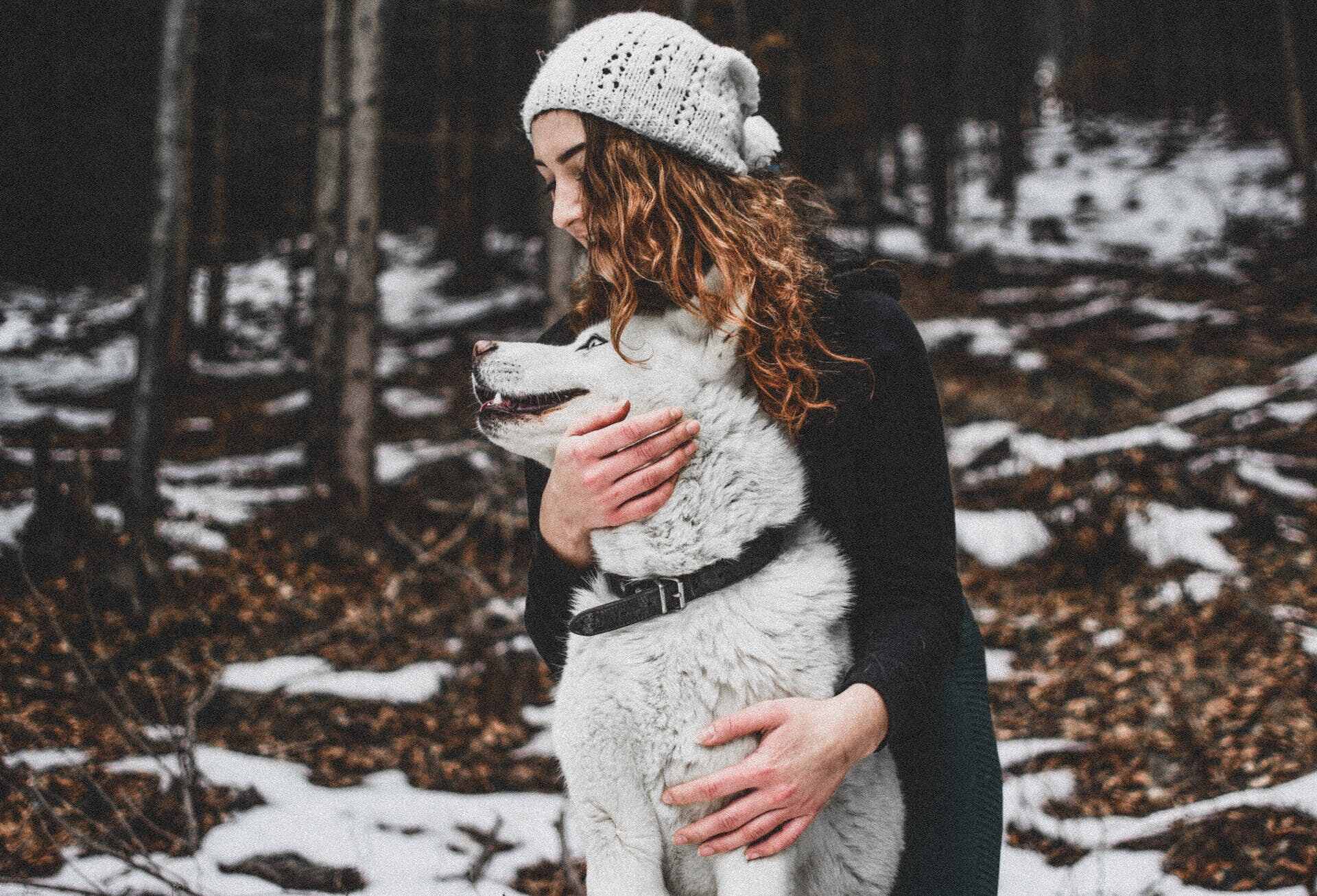 A woman hugging a dog in a forested area
