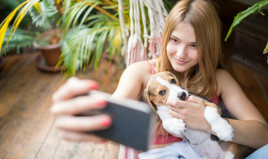 A girl taking a selfie with her puppy