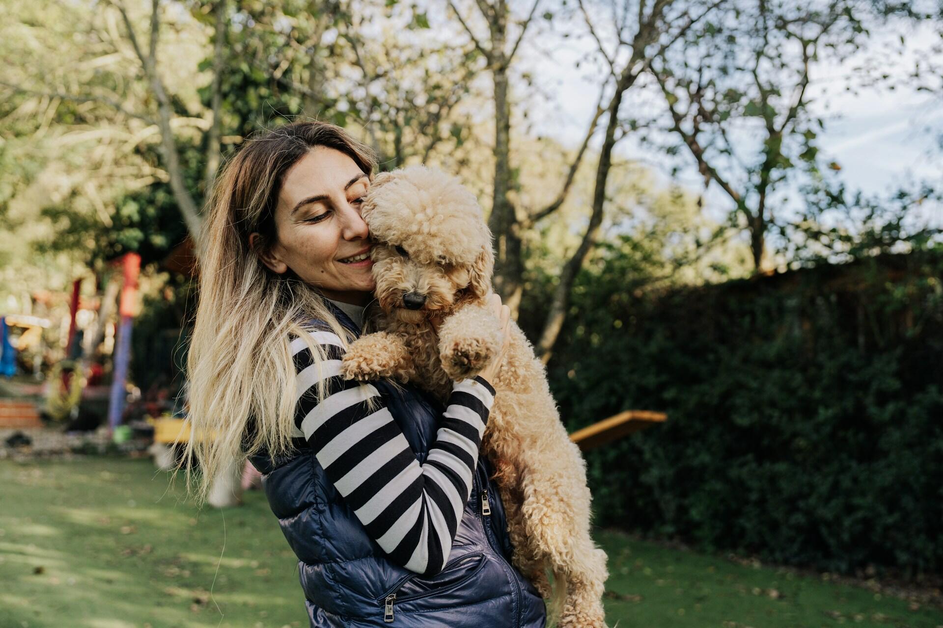 A woman hugging a puppy in a garden