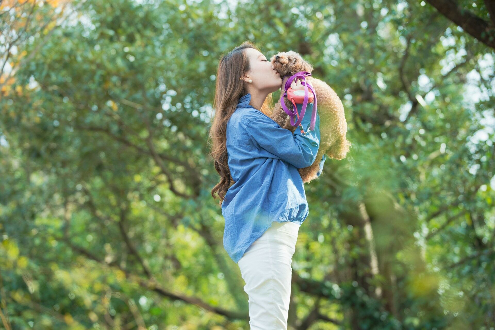 A woman hugging a small dog in a garden 