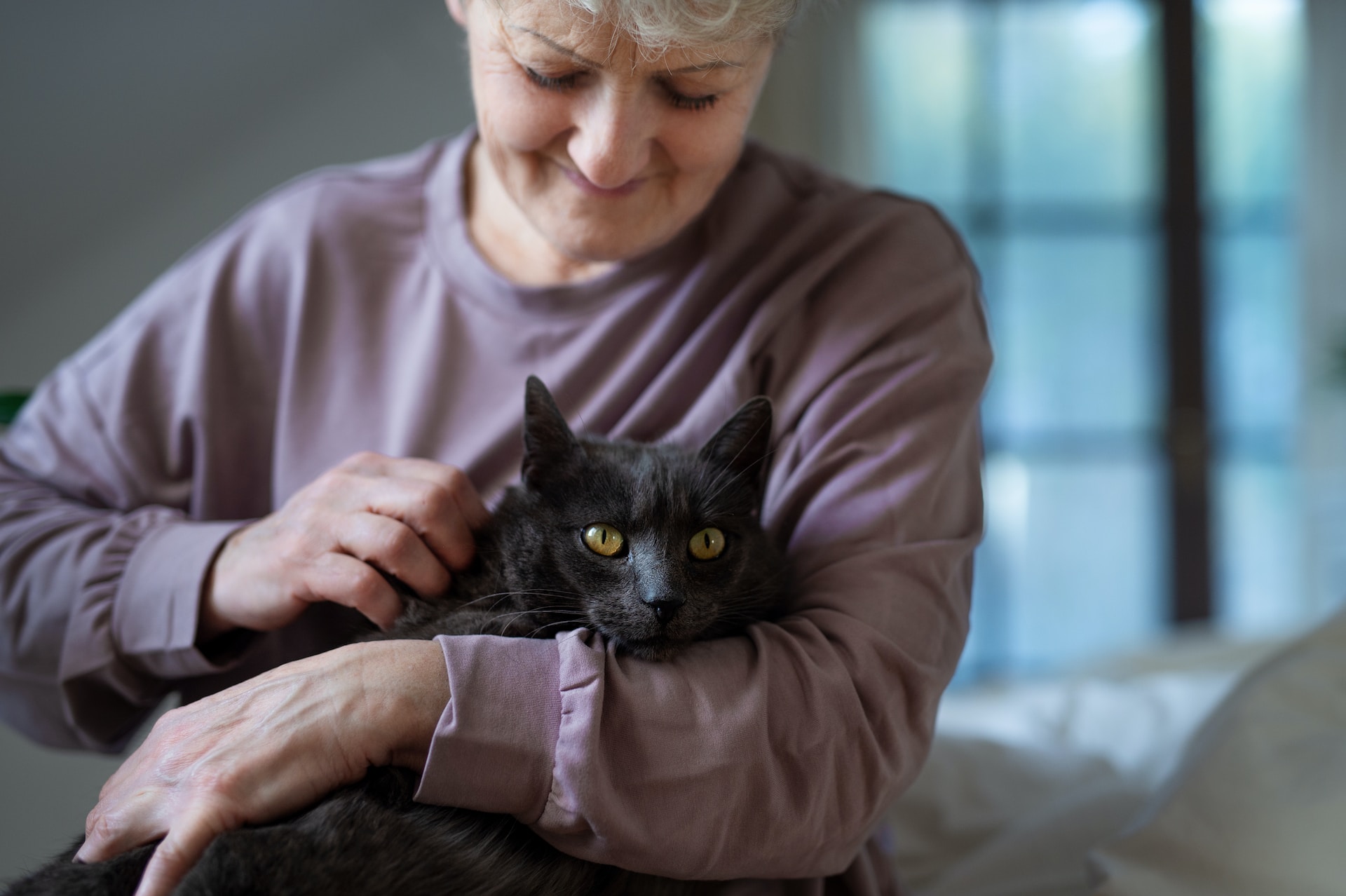 A woman holding a black cat in her arms