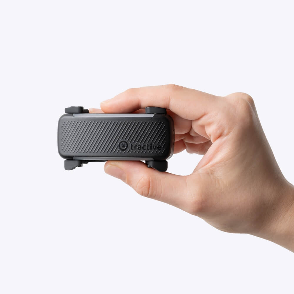 nærbilde av en hånd som holder en hvit Tractive GPS-tracker